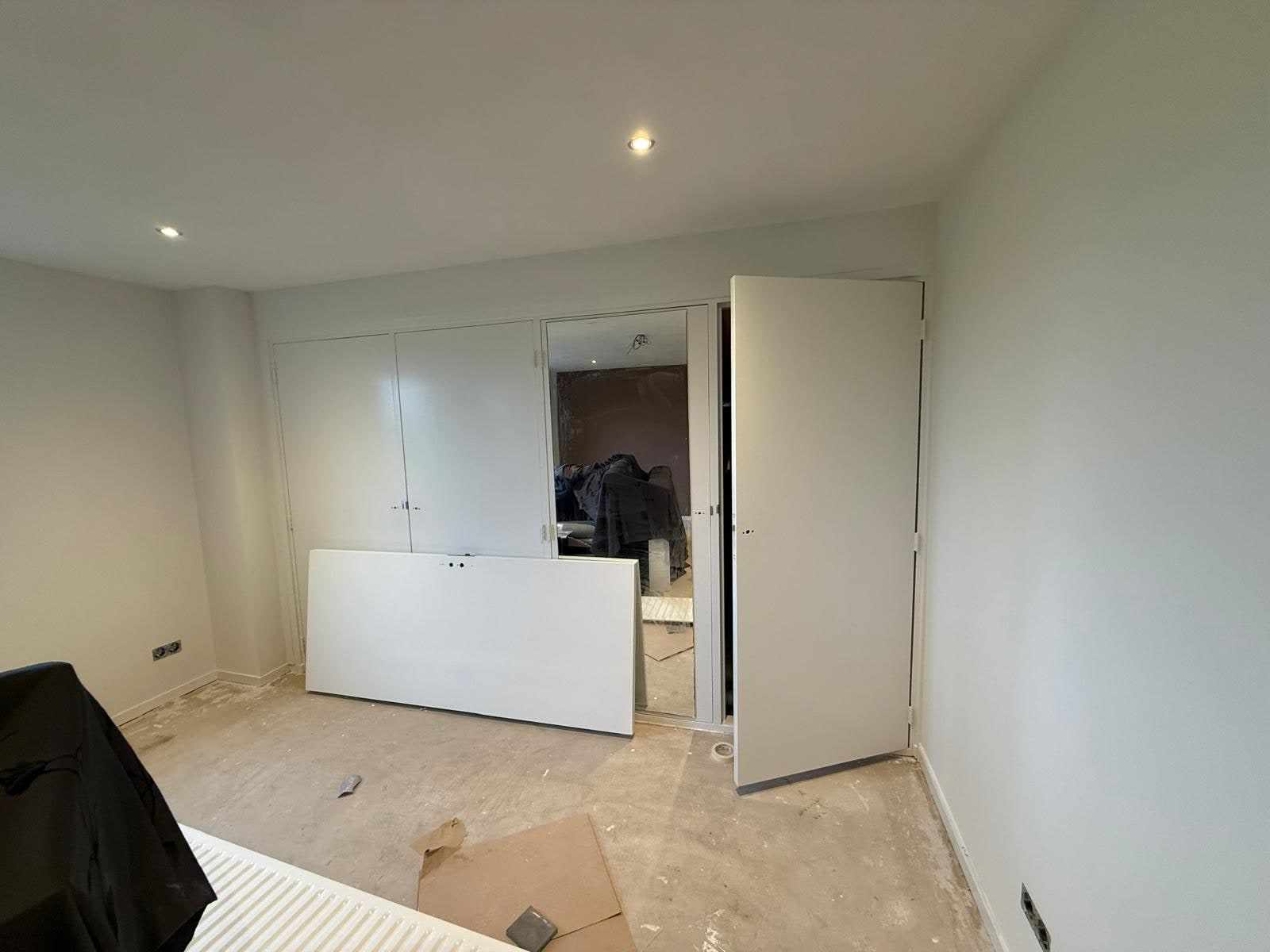 Kamer met witte wanden en plafond, keukenkast en dekzeil op de kale vloer