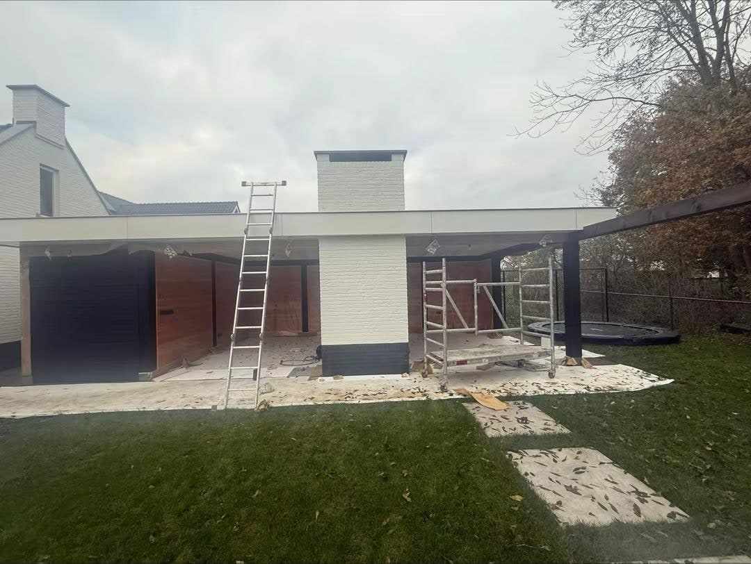 Tuin met de overkapping, ladders tegen de gevel en afdekzeilen op het gras