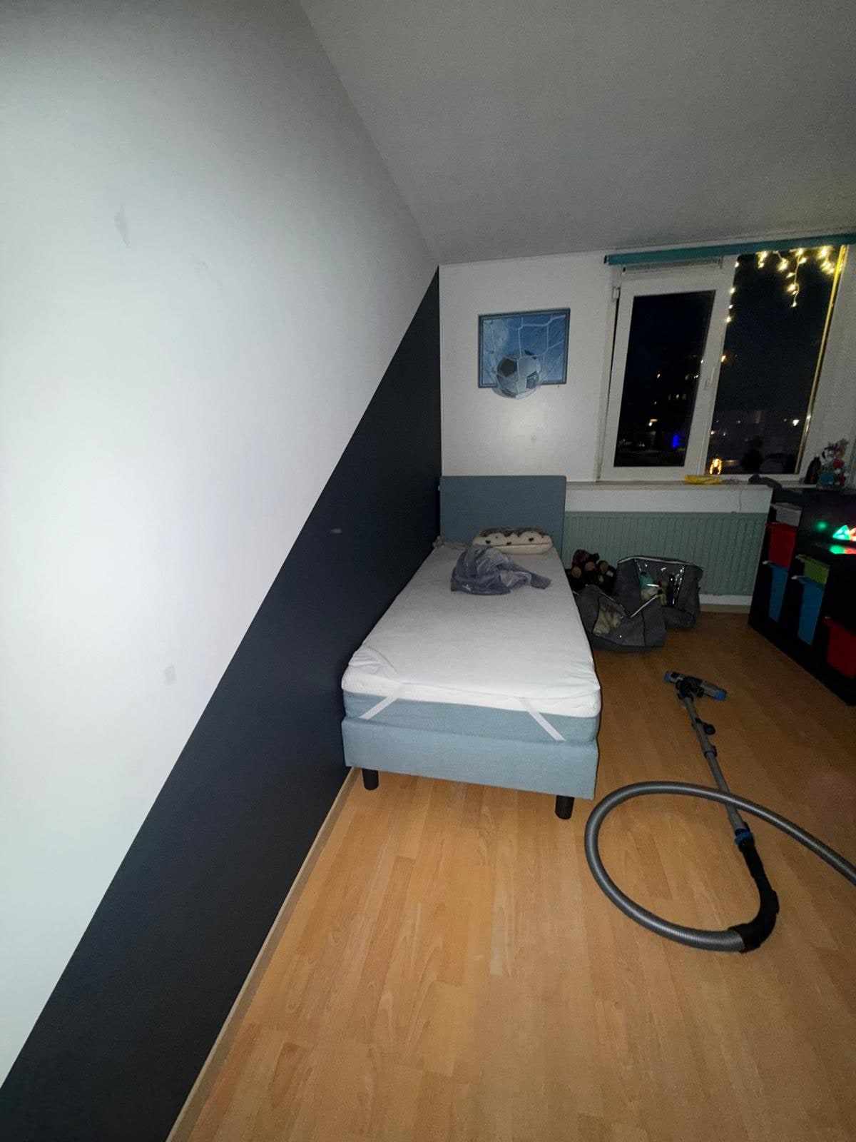 Kinderkamer met wit plafond en donkerblauwe wand achter het bed