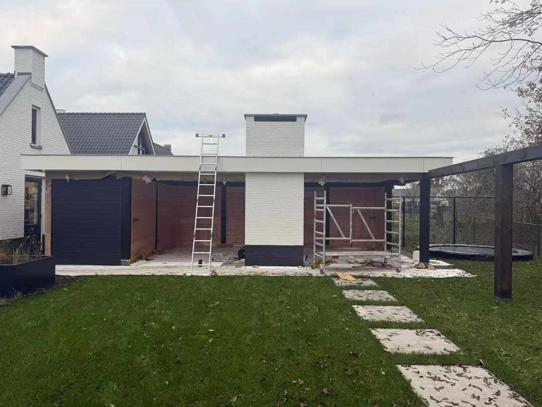 Achtertuin met de woning en overkapping, ladders klaargezet voor het schilderwerk