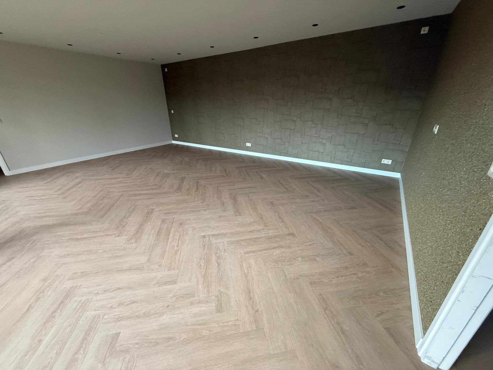 Kamer met een donkere structuurwand en lichte zijwanden boven de visgraatvloer
