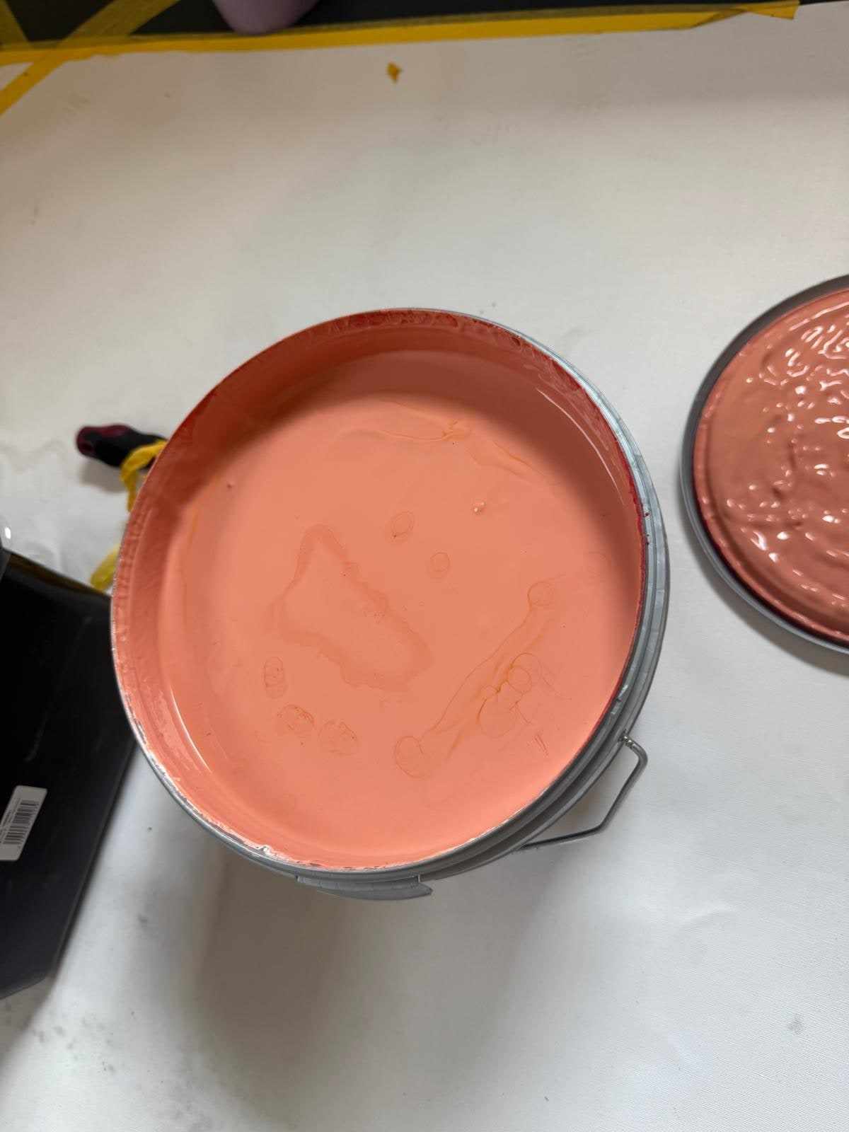 Geopend verfblik met terracotta muurverf op de afgedekte vloer