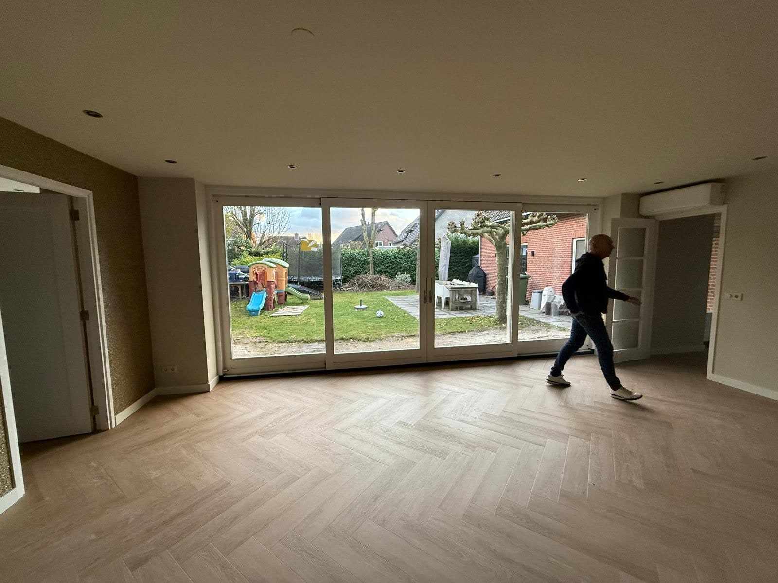Woonkamer met egaal beige wanden, wit plafond en witte binnendeuren aan de tuinzijde