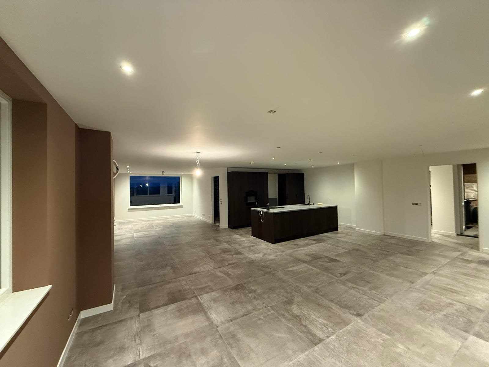 Open woonkeuken met witte wanden en plafond en een taupe geschilderde muur