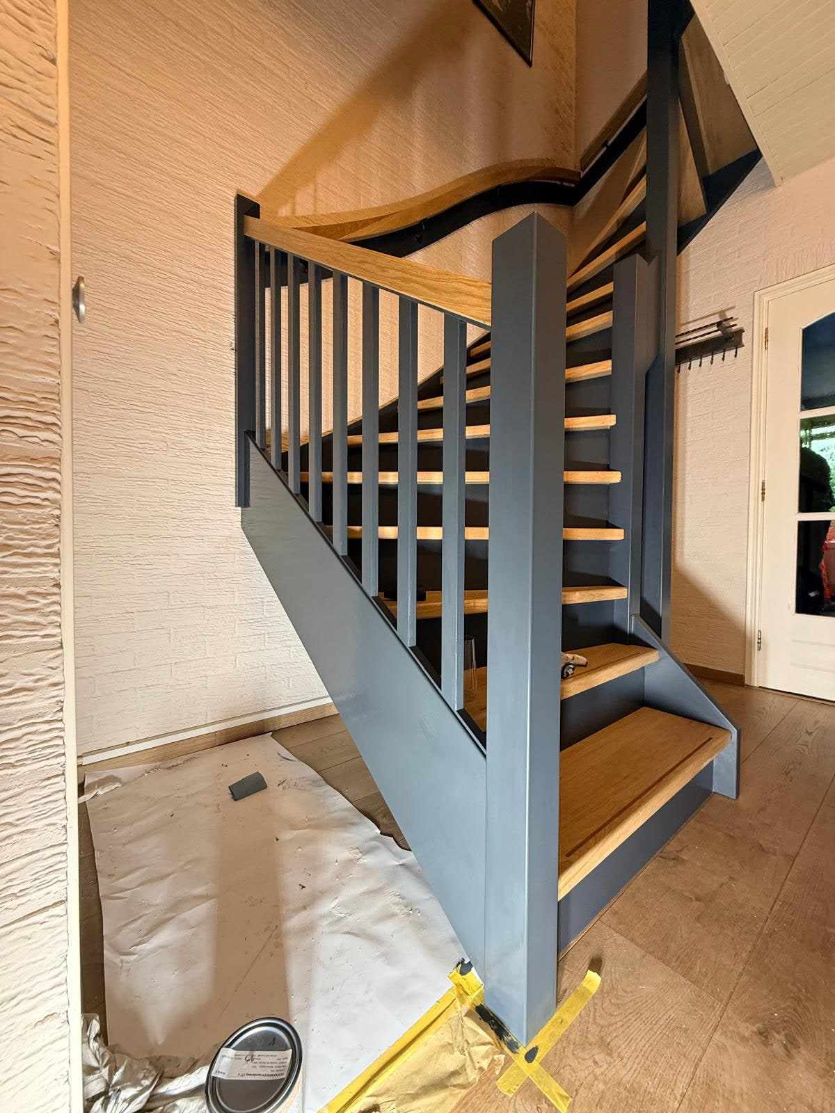 Trap met blauwe balustrade, de vloer eronder afgedekt met een stofdoek