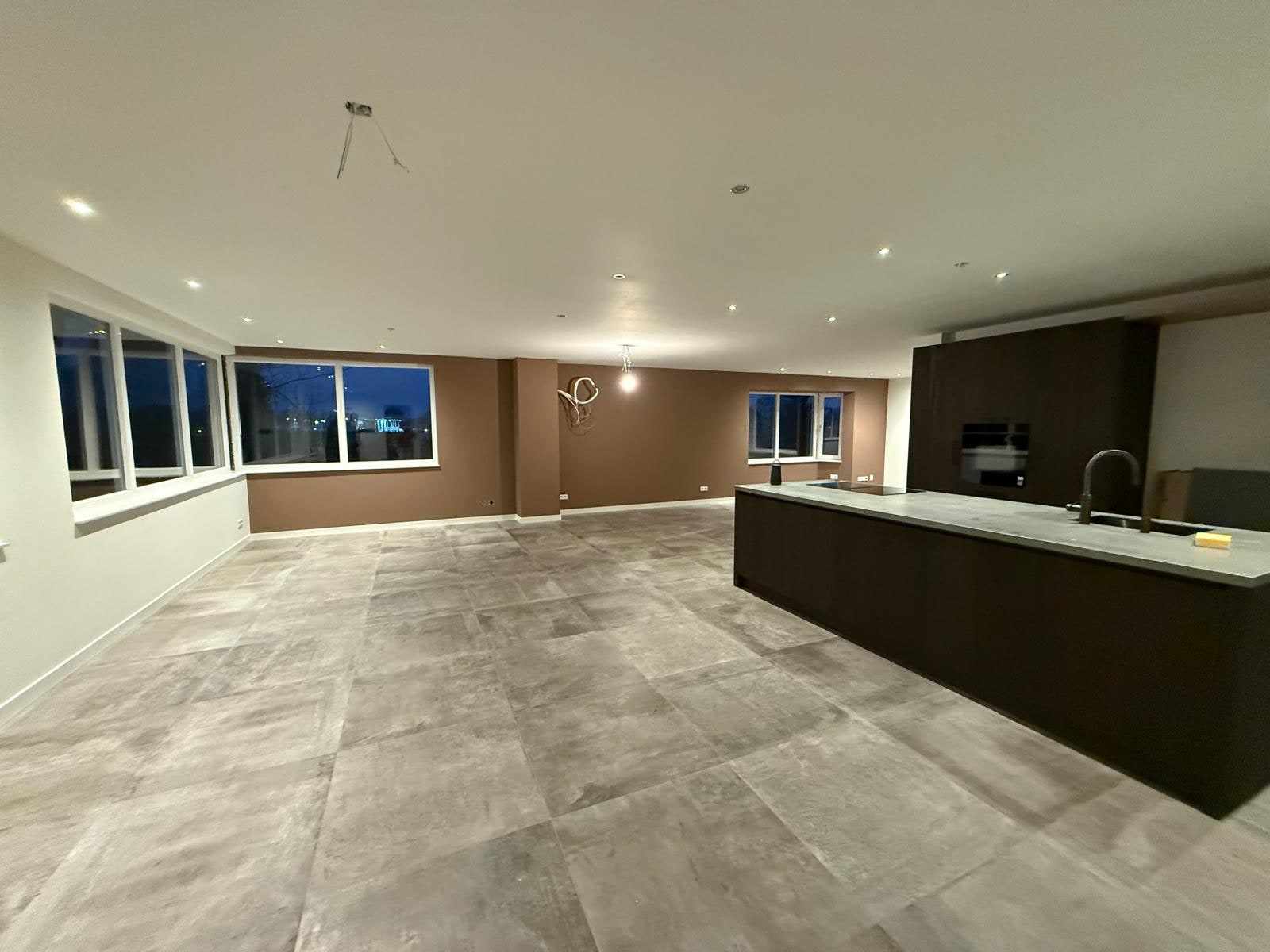 Woonkeuken met kookeiland, wit plafond en taupe wanden rond de raampartij