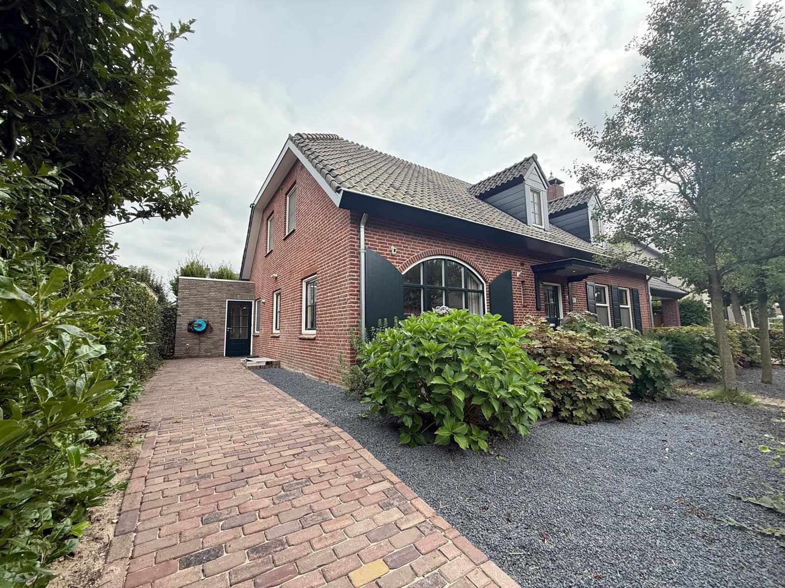 Oprit langs de nog rode bakstenen zijgevel van de woning