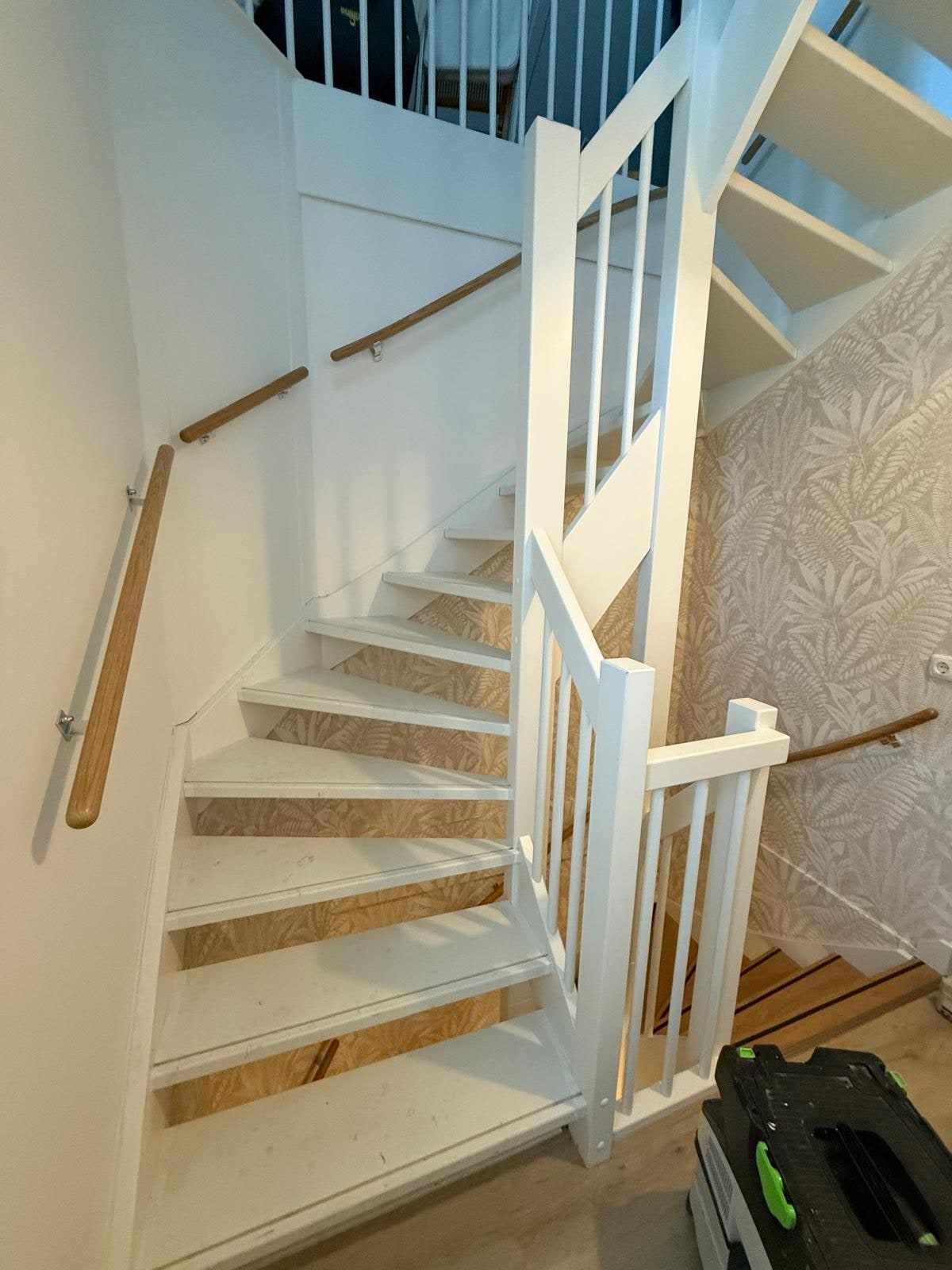 Trap met nog kale houten treden en een gereedschapskoffer onderaan