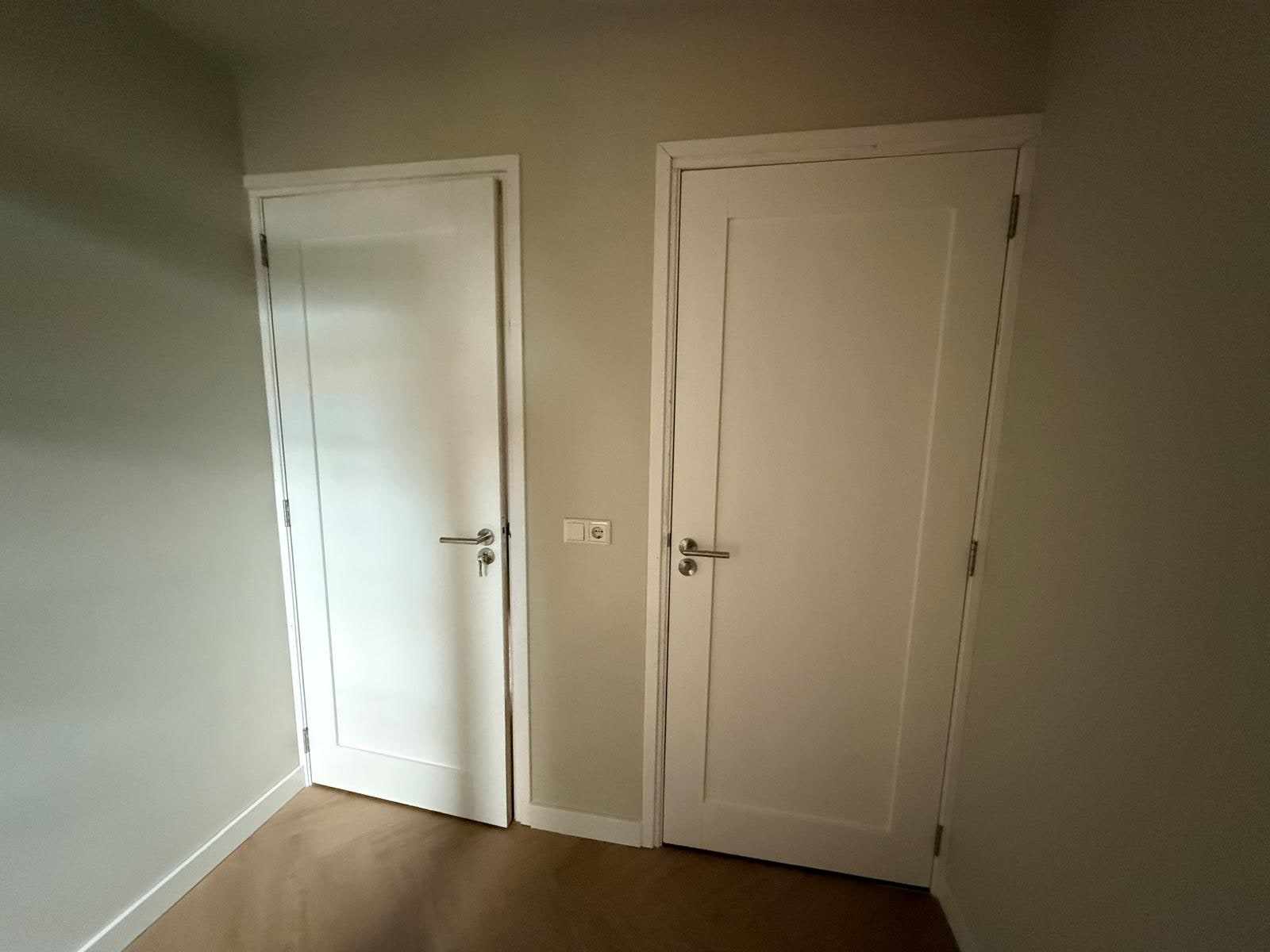 Twee wit gelakte binnendeuren naast elkaar in een beige geschilderde wand