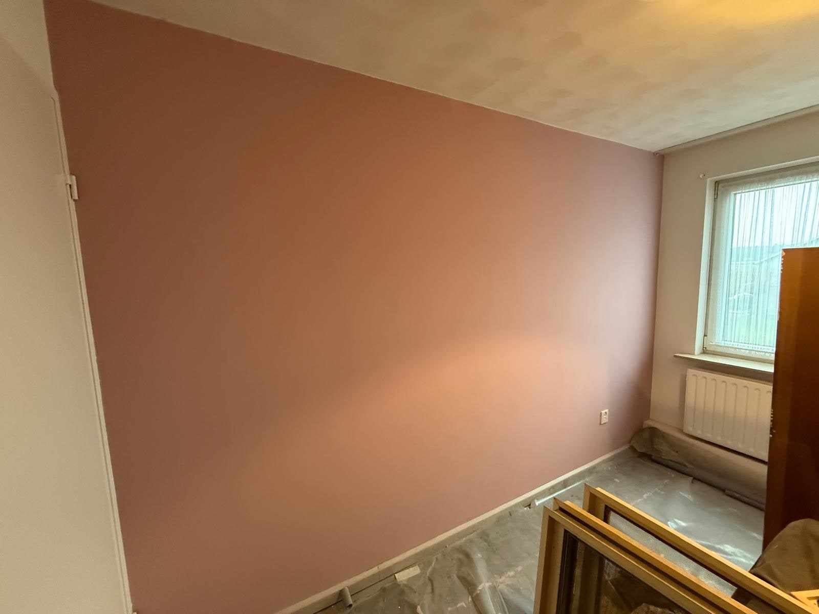 Kamerhoek met een zacht terracotta wand boven de radiator naast het raam