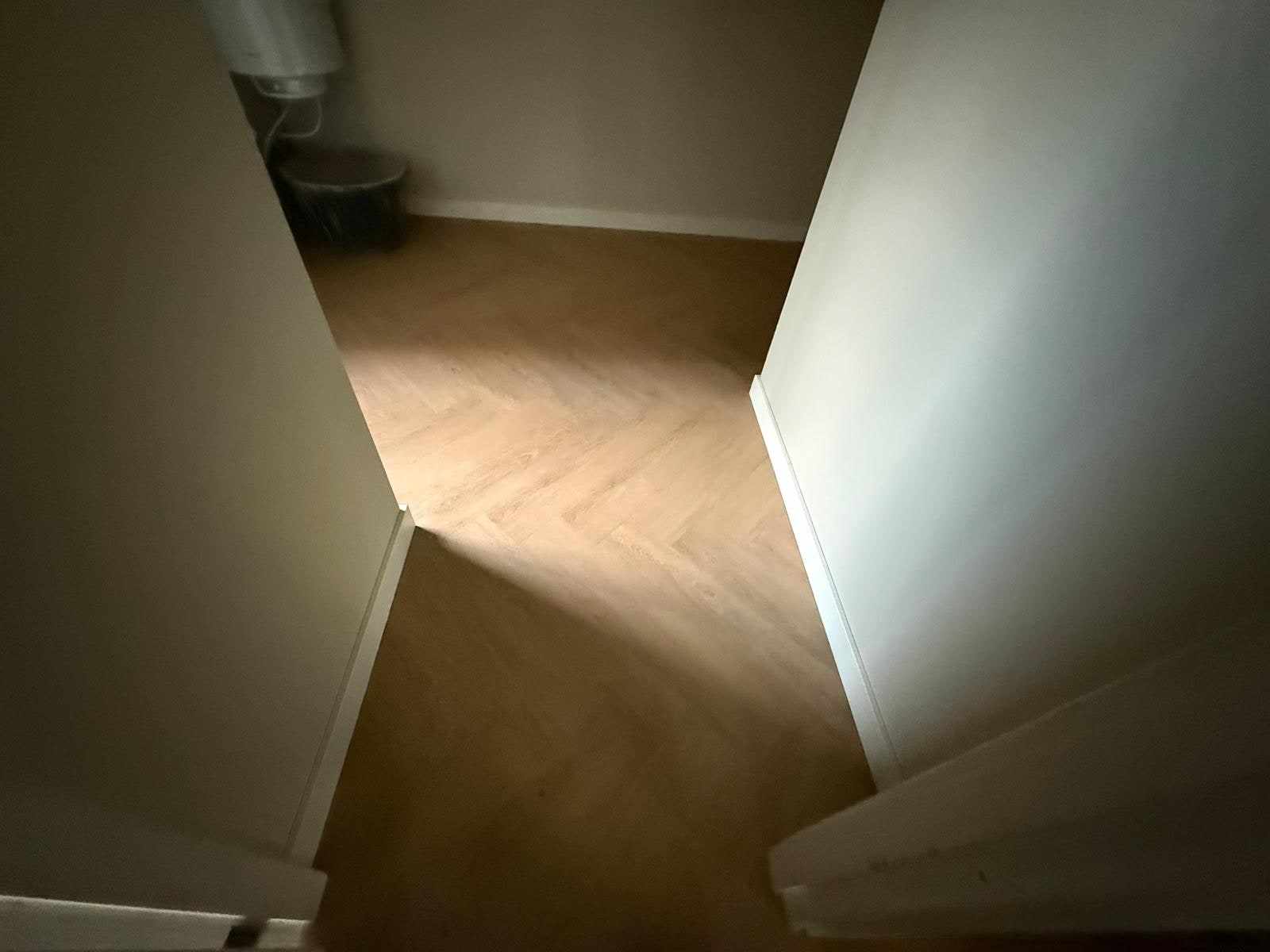 Hal met beige wanden en een witte plint langs de visgraatvloer