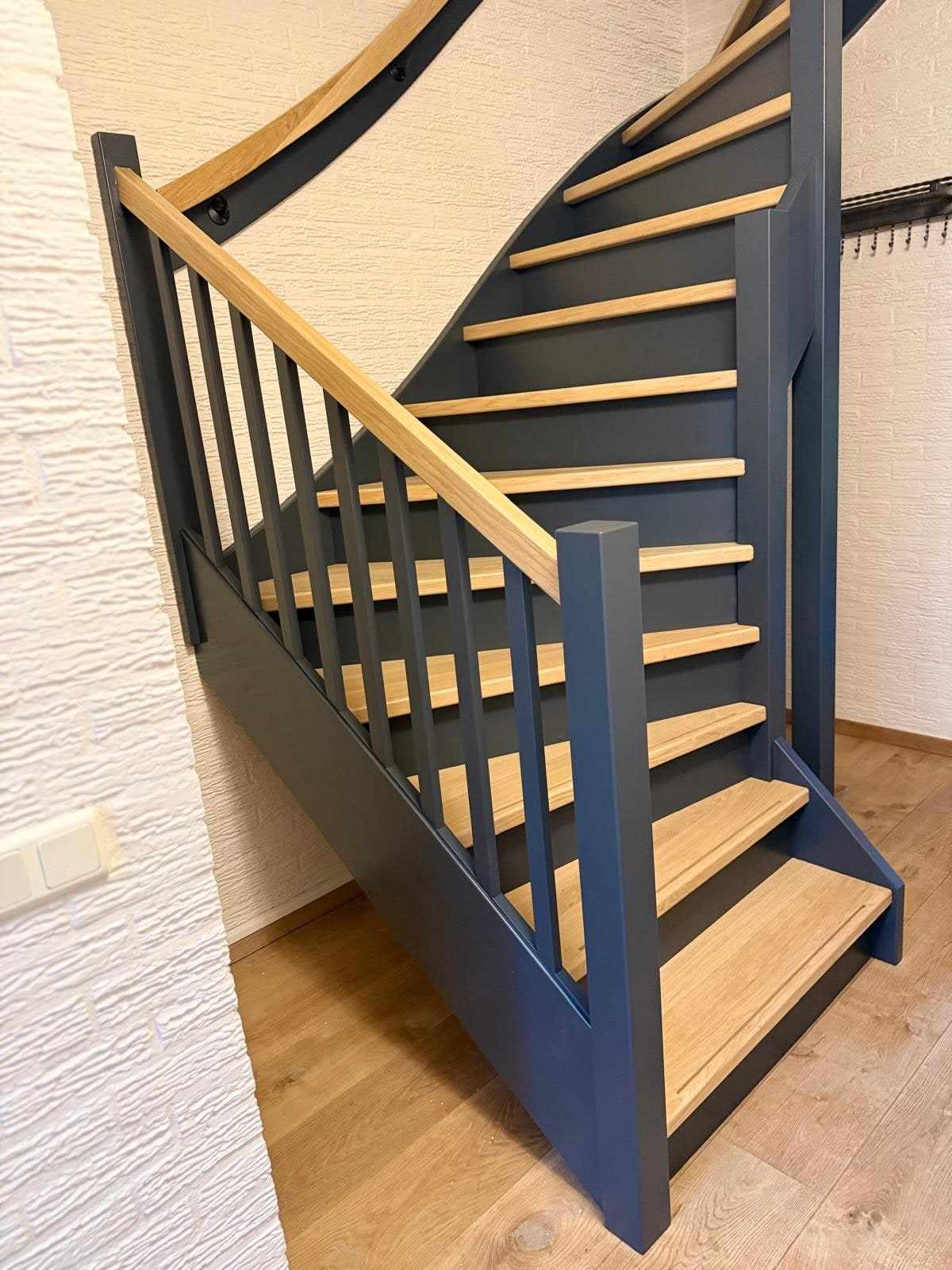 Balustrade met donkerblauwe balusters en een eiken handlijst boven de eiken treden