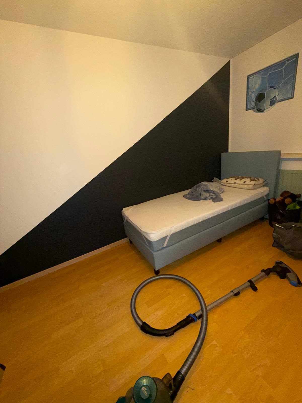 Kinderkamer met een strak afgetekend donkerblauw vlak op de schuine wand