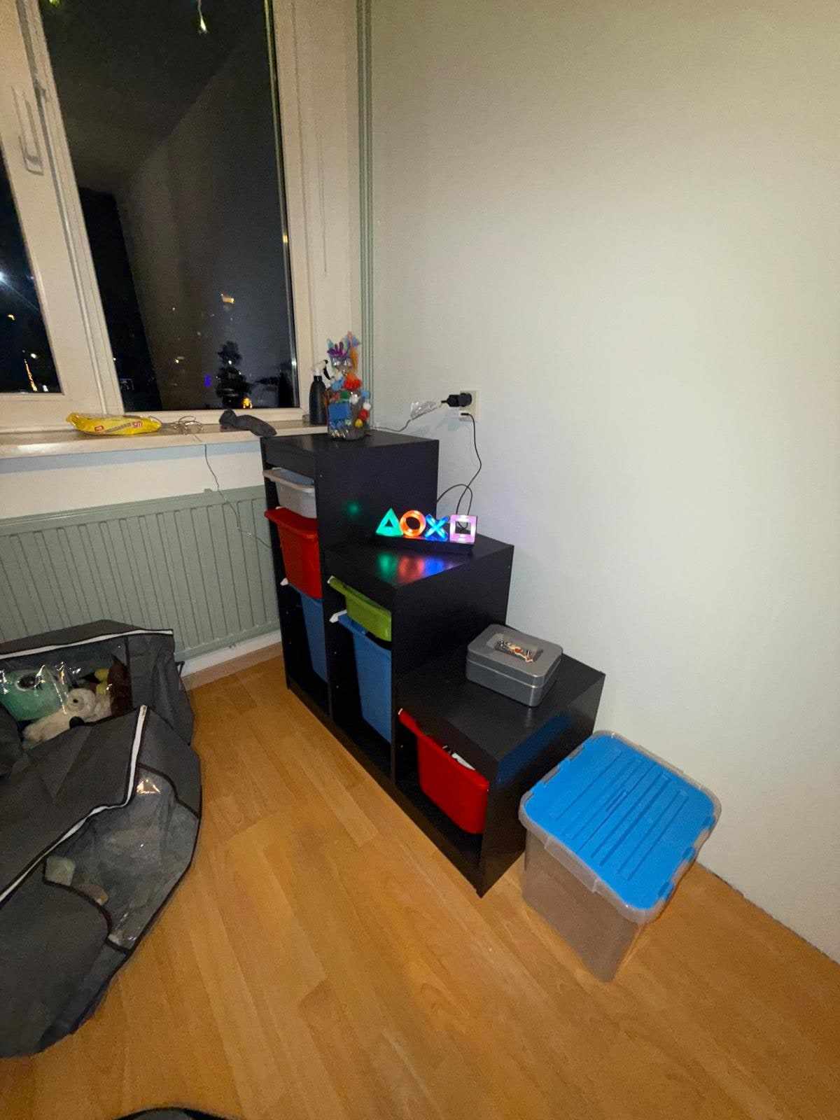 Raamwand met groene lambrisering en speelgoedkast in de kinderkamer