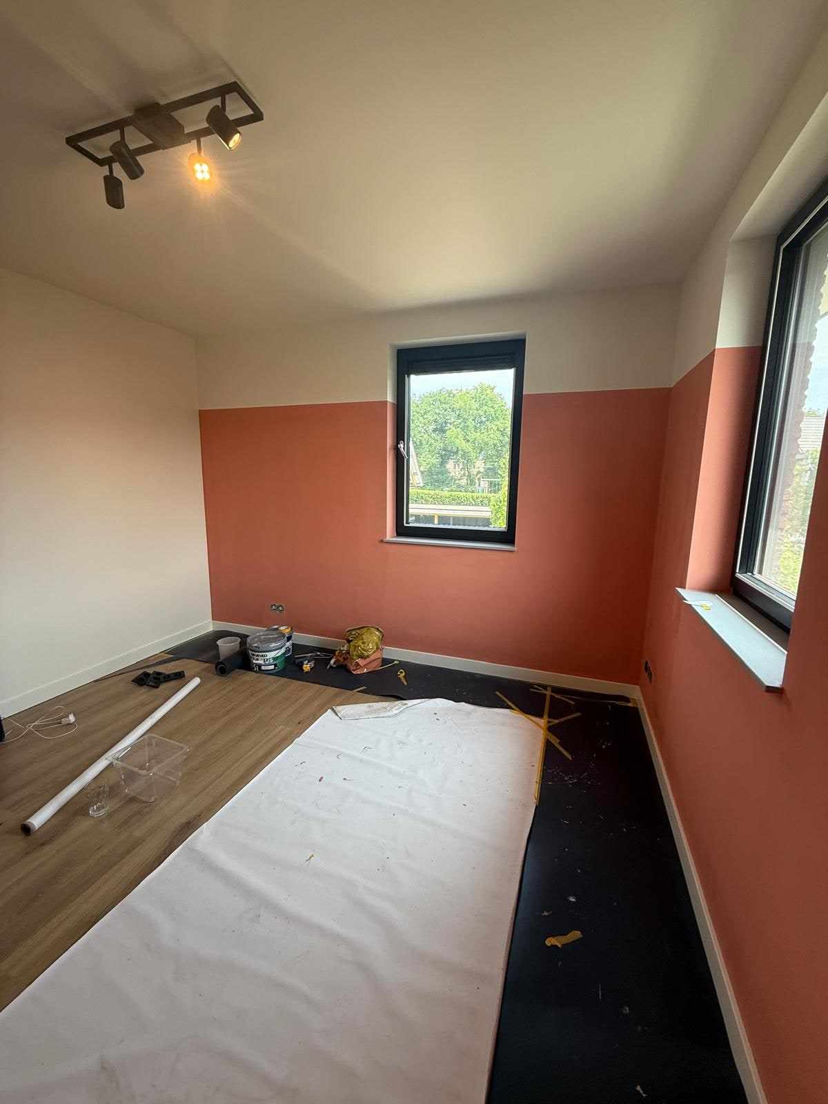 Terracotta geschilderde wanden met witte bovenrand rond het raam