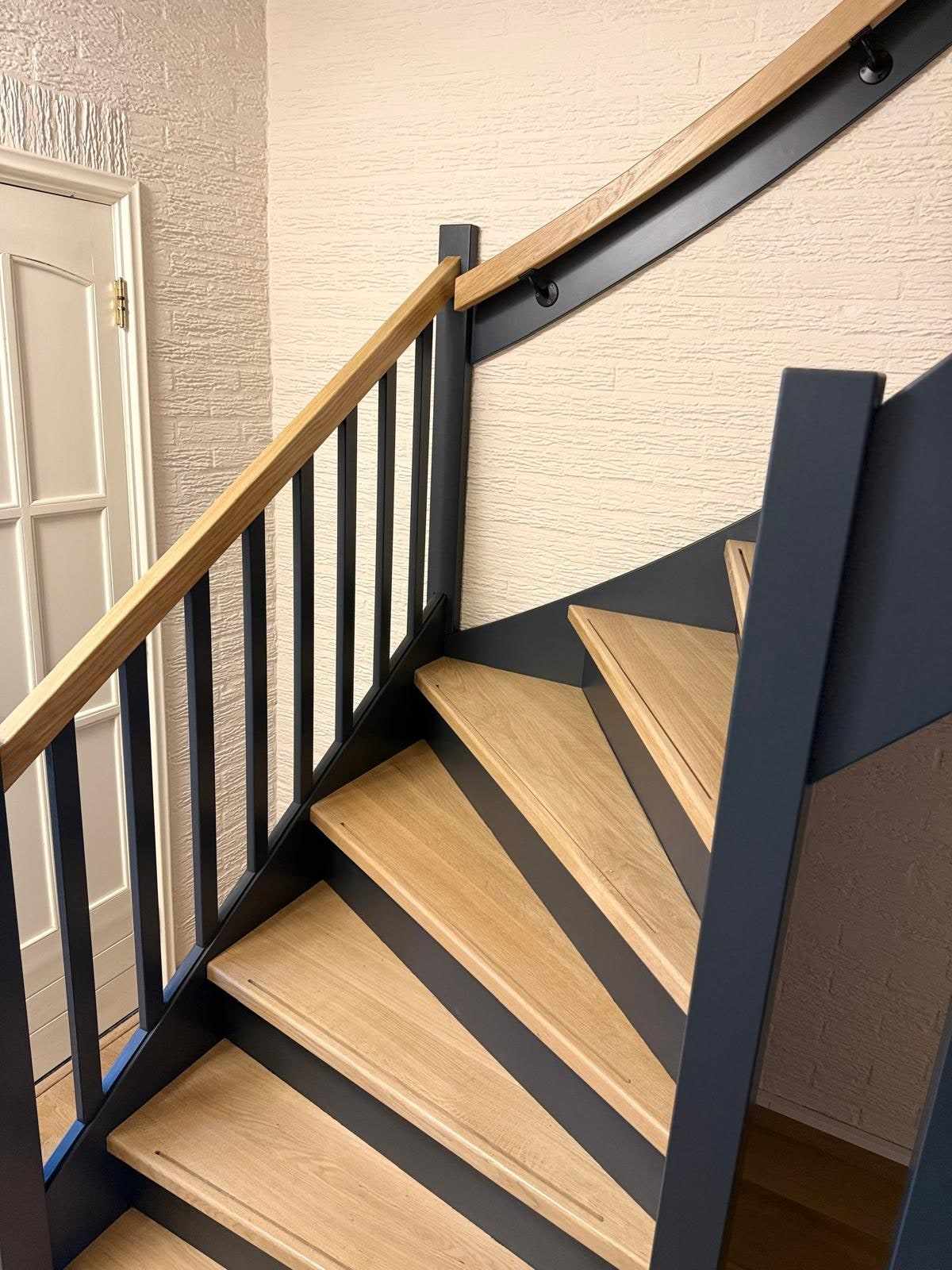 Kwartslag met eiken treden, donkerblauwe stootborden en een eiken handgreep aan de wand