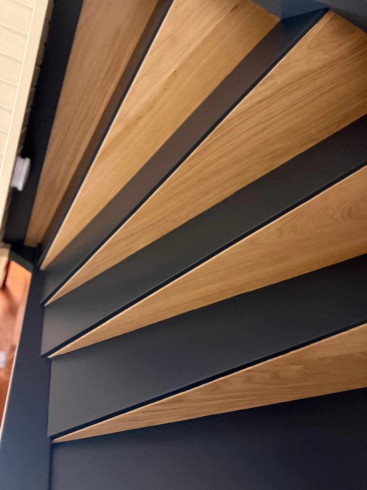 Detail van blanke eiken treden met donkerblauw gelakte stootborden en trapwang