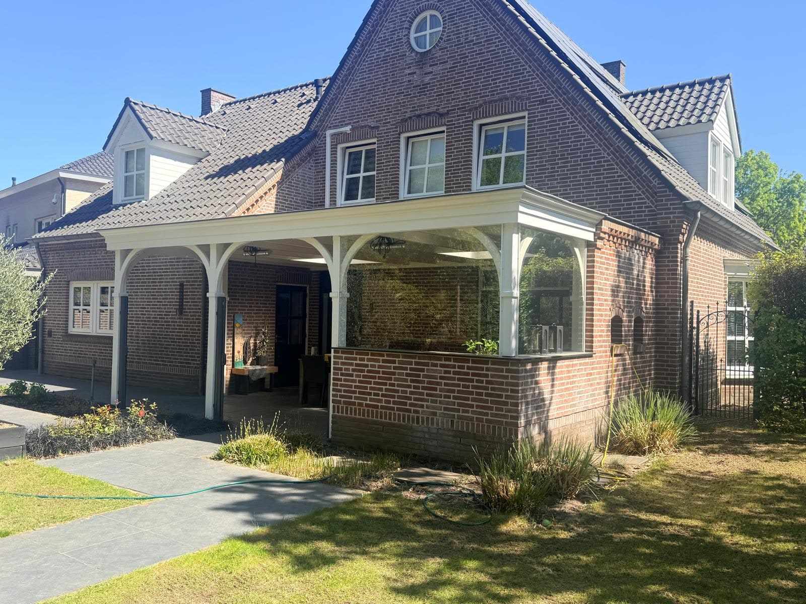 Voorzijde van de woning met houten overkapping, gezien vanaf het tuinpad