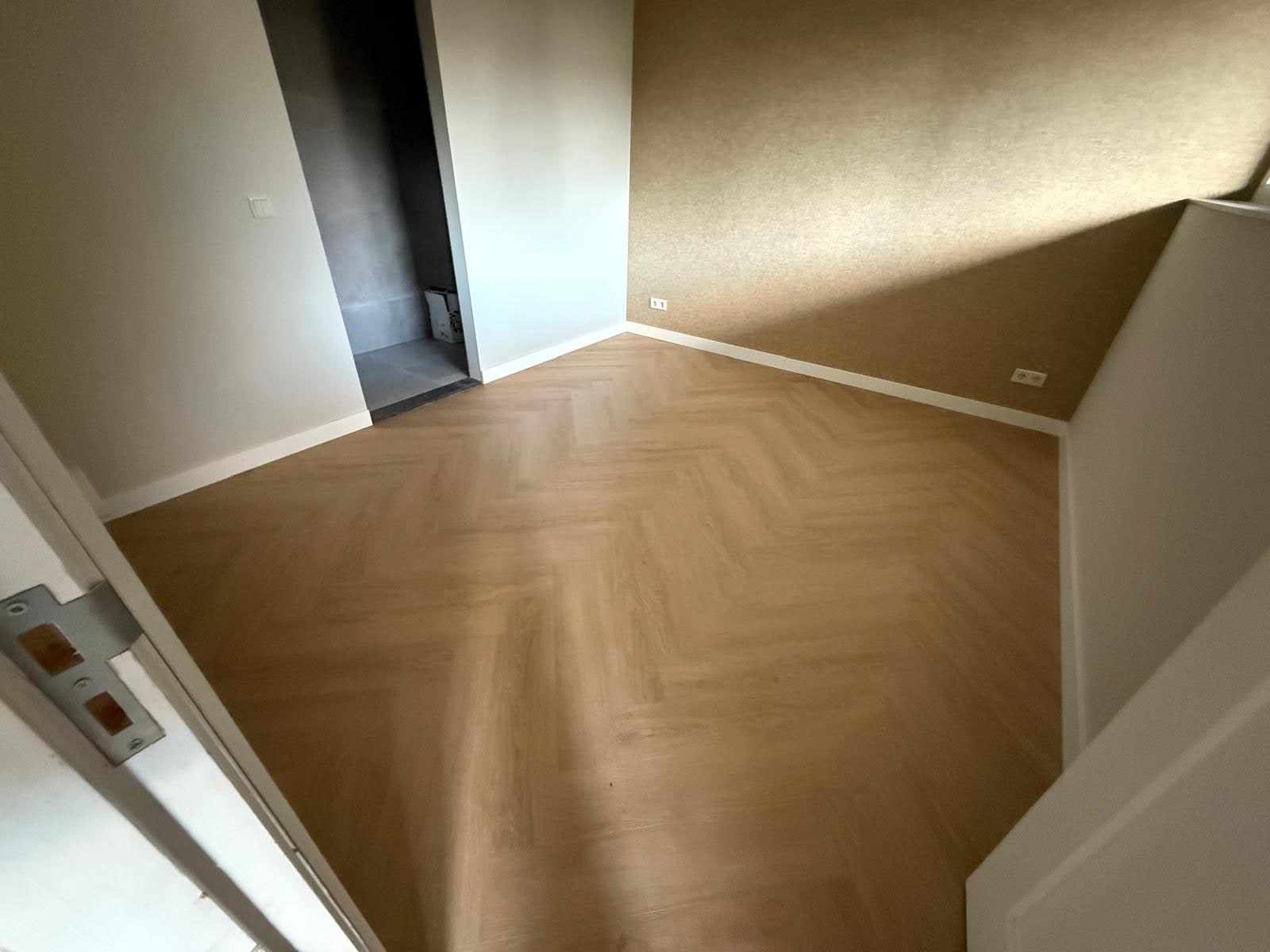 Kamer met egale beige wanden zonder zichtbare naden of scheuren boven de visgraatvloer