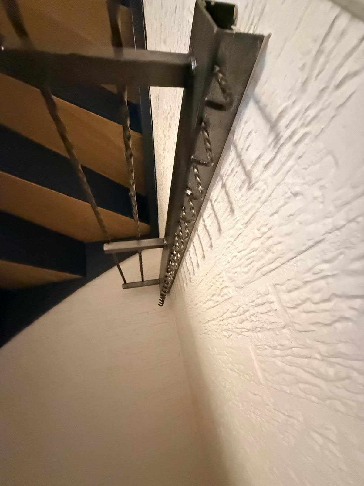 Detail van de trapwang tegen de structuurwand, met de blauwe lak strak afgezet