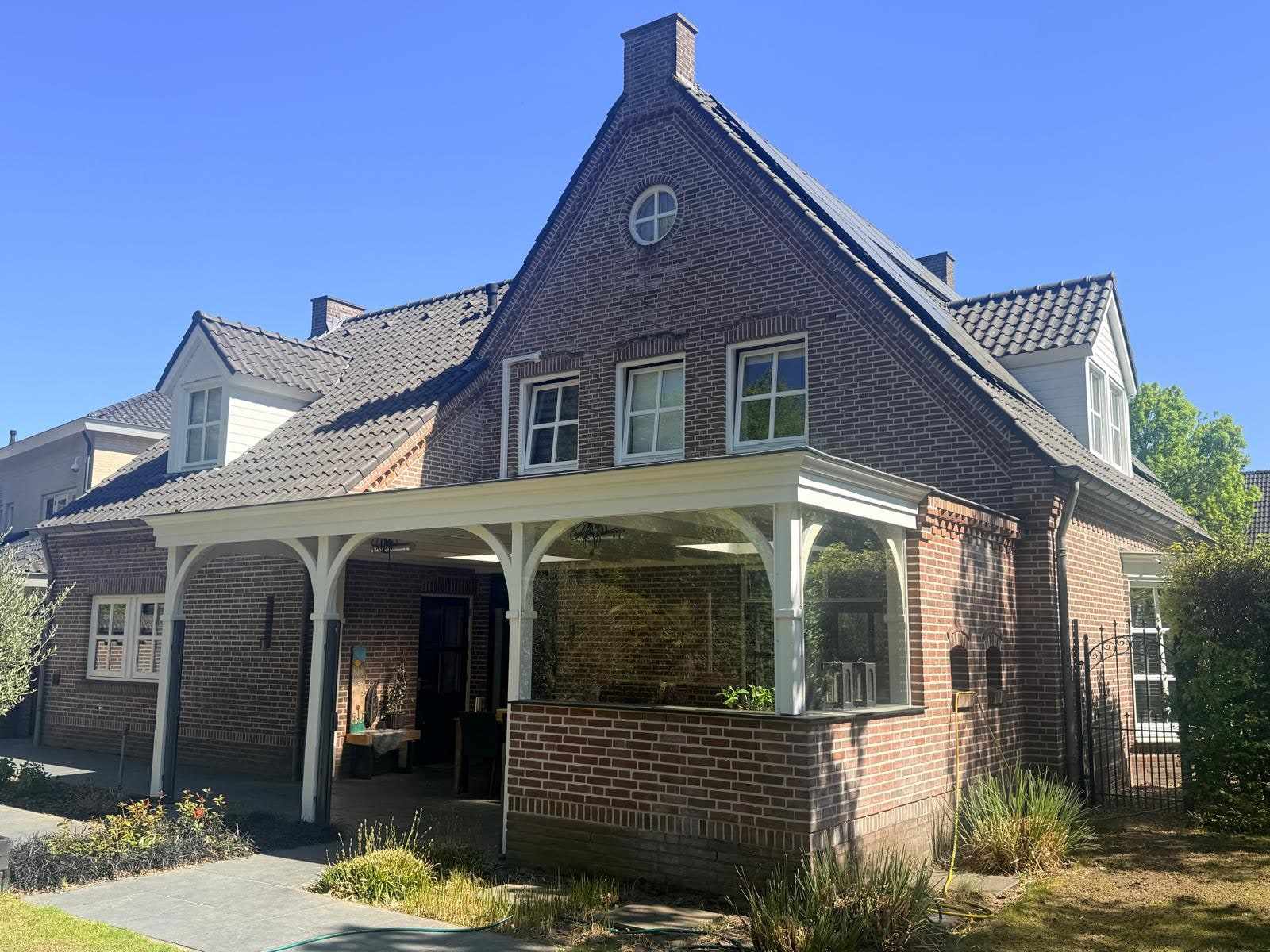 Zijaanzicht van de woning met de overkapping en de nieuw gelakte kozijnen