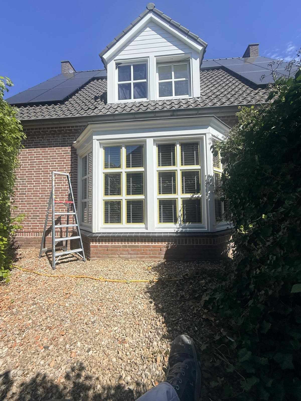 Dakkapel met witte kozijnen en een rolsteiger op het grind ernaast