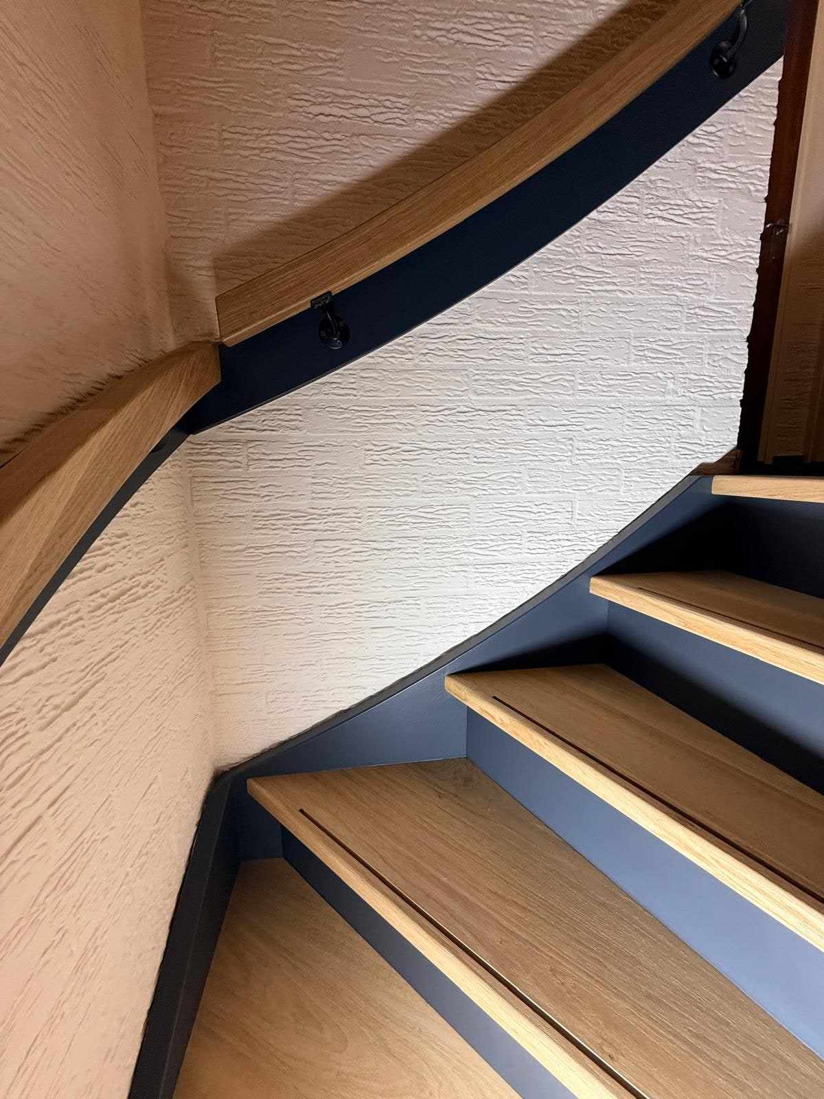Trapdetail waar de donkerblauwe trapboom overgaat in de blanke eiken treden