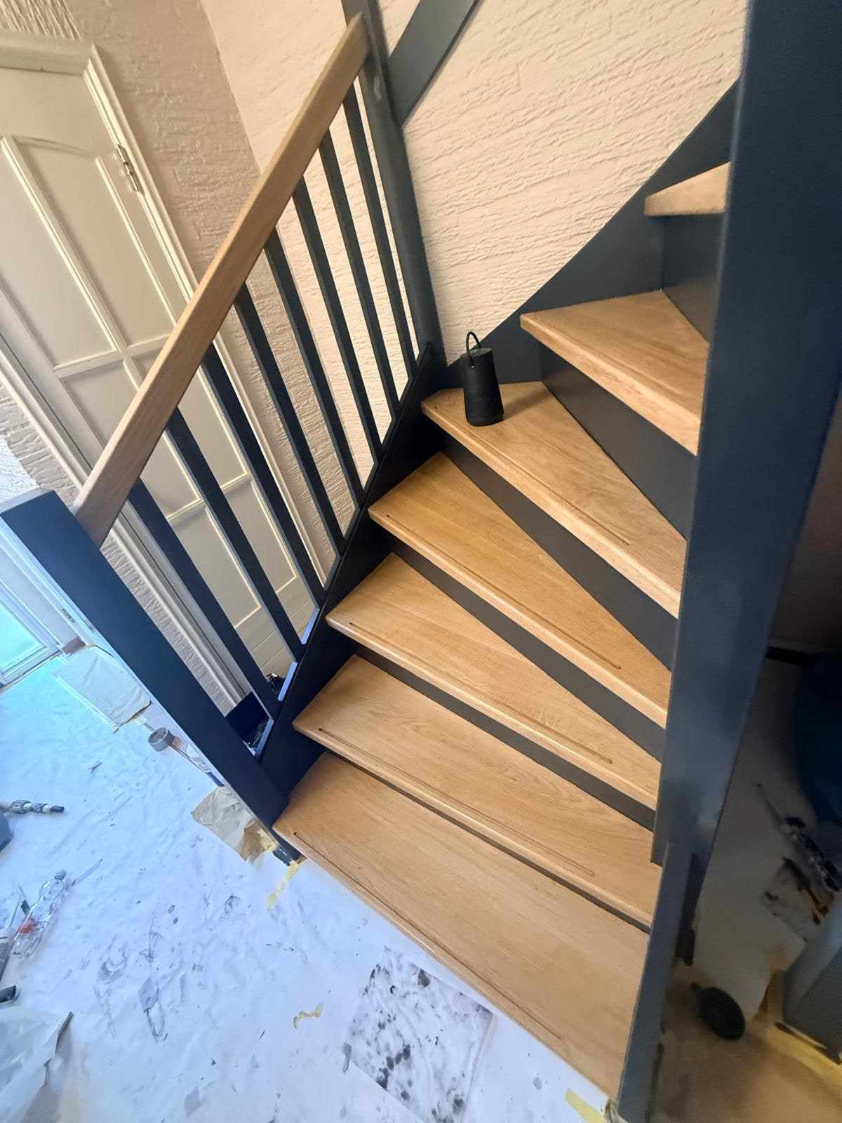 Trap met blauwe balustrade boven een met folie afgedekte vloer