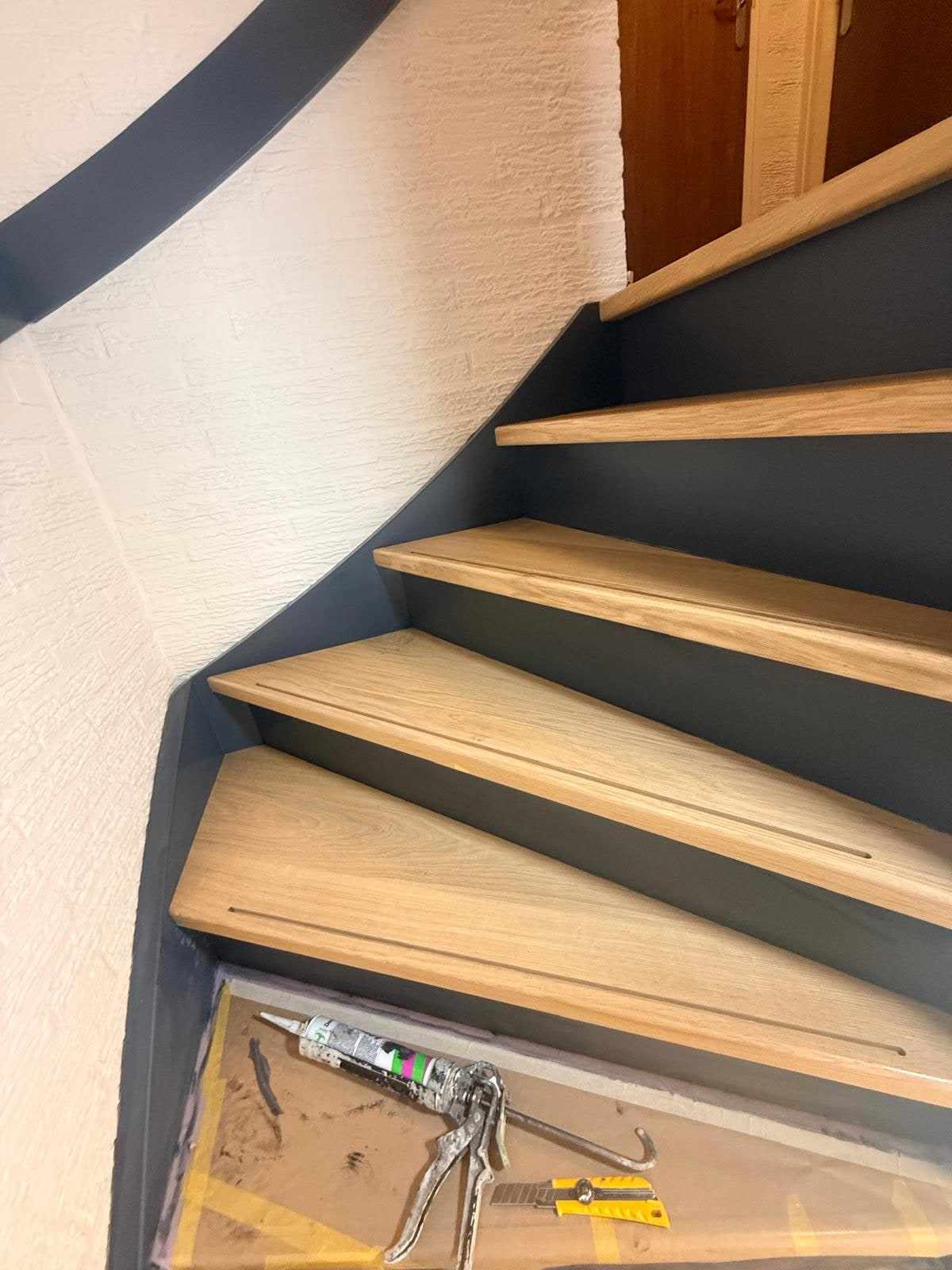 Onderste treden van de trap met gereedschap op de afgedekte vloer ernaast
