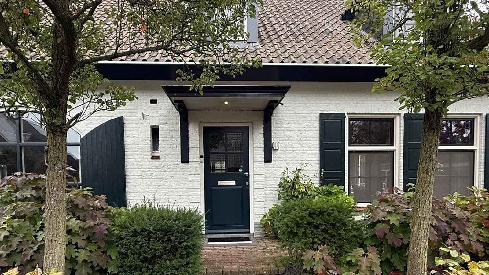 Wit geschilderde woning met donkergroene luiken na buitenschilderwerk door Petar A.S.A.P.